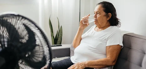 An older woman drinking a glass of water indoors