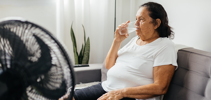 An older woman drinking a glass of water indoors