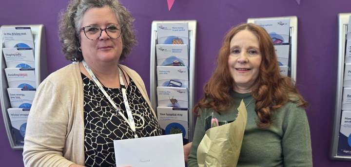 Age UK Shropshire Telford & Wrekin support worker Pauline receiving flowers and a card from Tracy Reynolds, Head of Help at Home.
