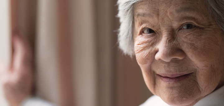 Older woman standing by curtains