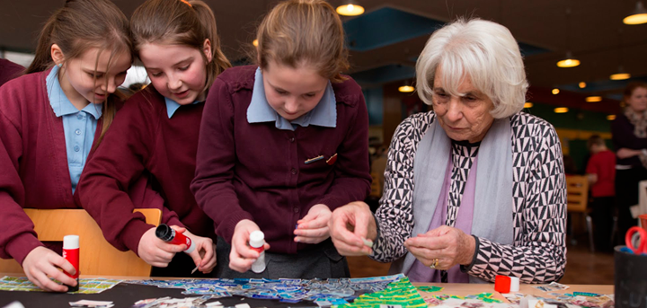 An older woman working with schoolchildren on an art project