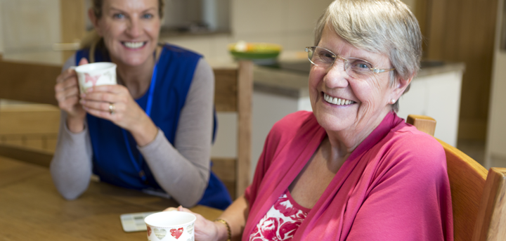 An older woman drinking tea with her support worker