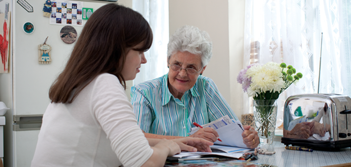 An older woman and a volunteer discussing paperwork