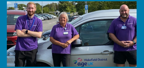 Members of the Hospital Transport Support Service standing beside a wheelchair suitable car