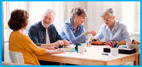 Group of senior people sat around a table, smiling and playing games