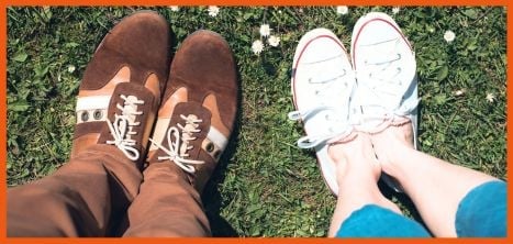 two pairs of shoes with feet and legs, standing on grass