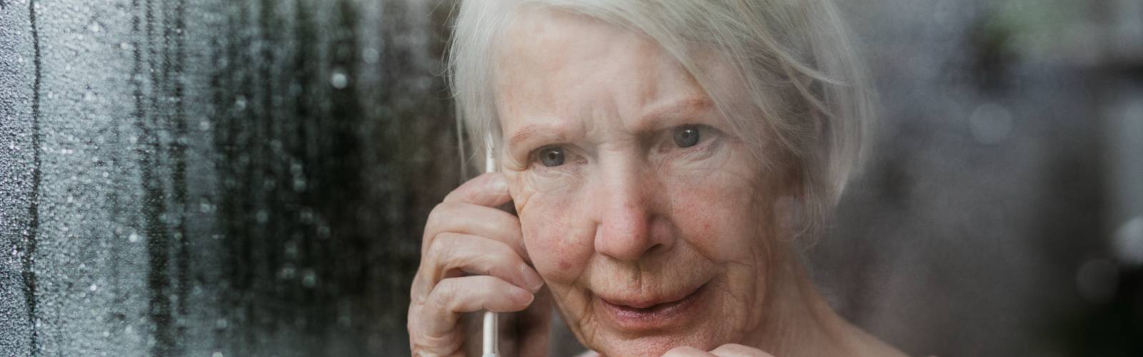 A woman looks worriedly out of her window during cold weather, while on the phone