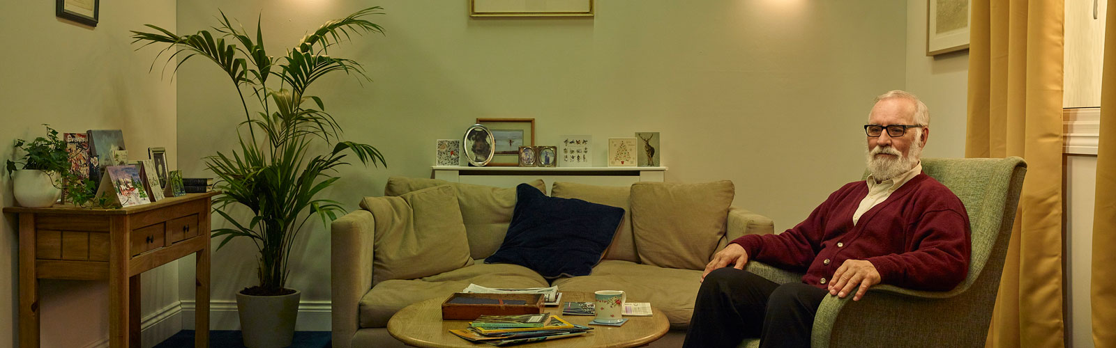 Colin sits in an armchair looking at the camera