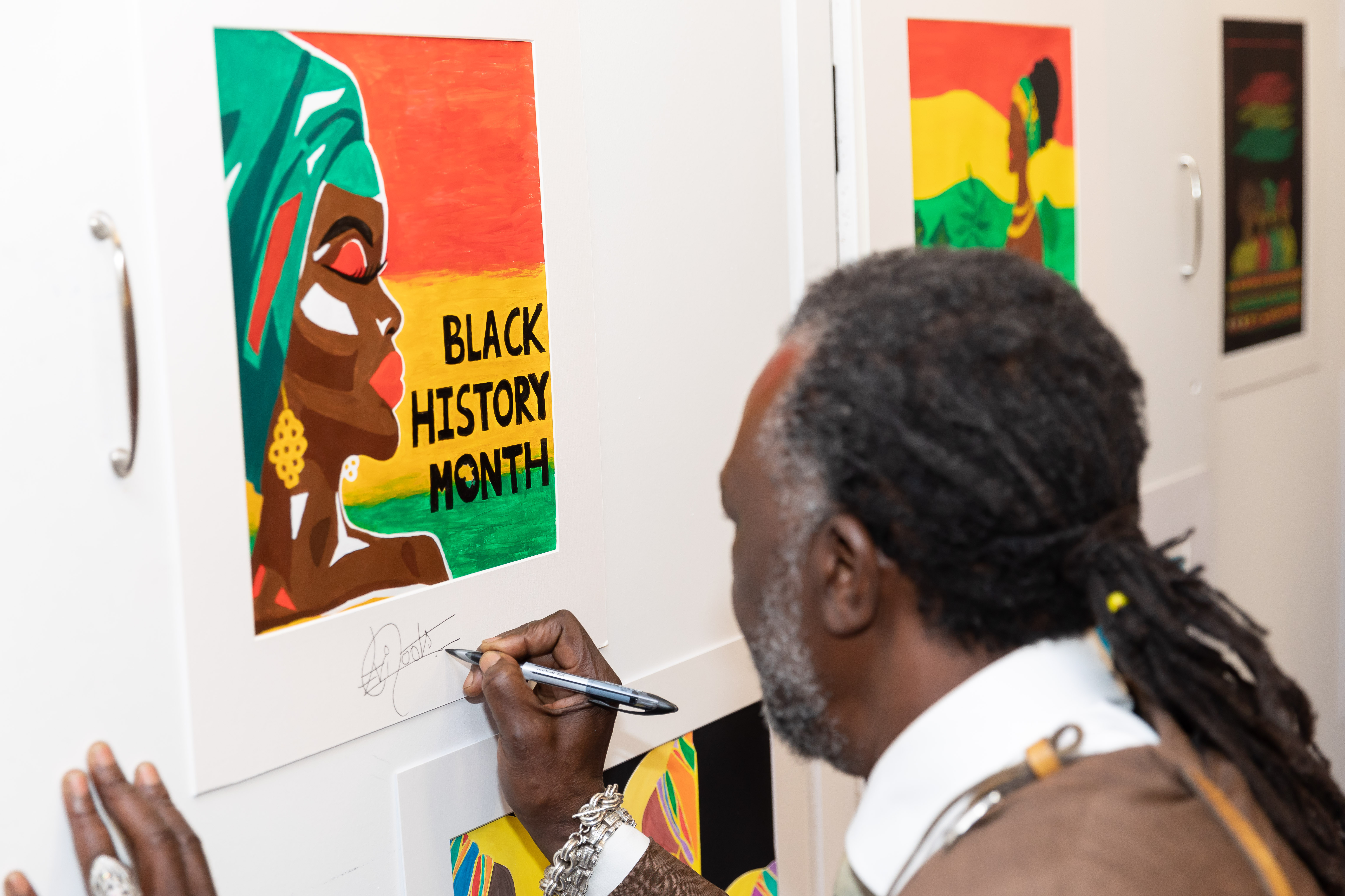 Levi signing some artwork created by Age UK Barnet for Black History Month