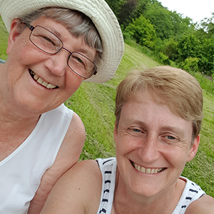 An older woman and her daughter smile at the camera