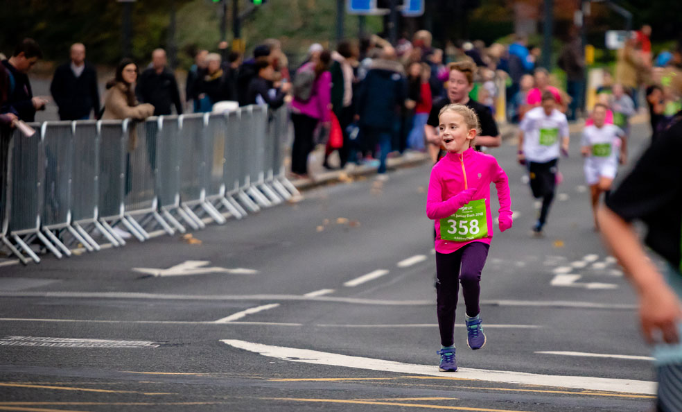 A young girl in a pink jersey running the Junior Dash