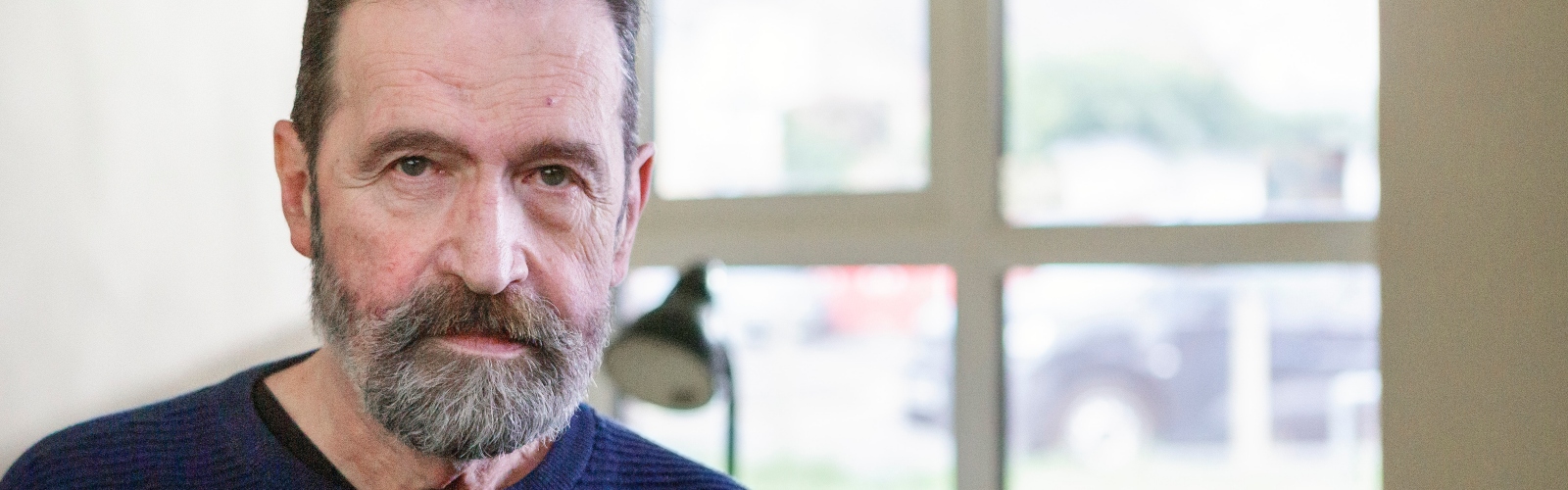 An older man with a beard stares into the camera