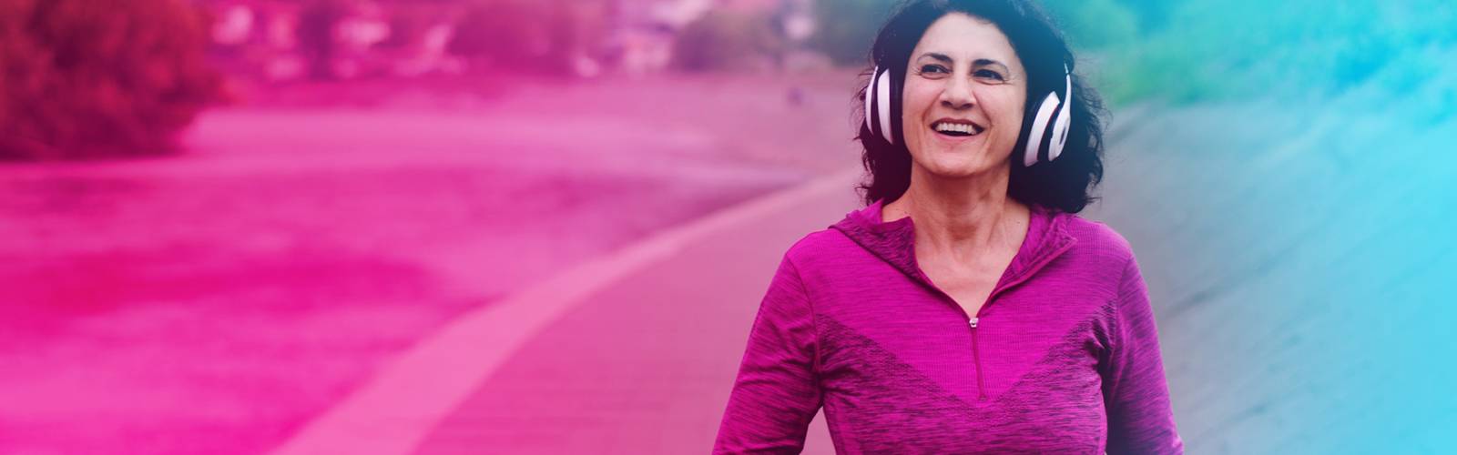 A middle aged woman wearing heaphones, out exercising