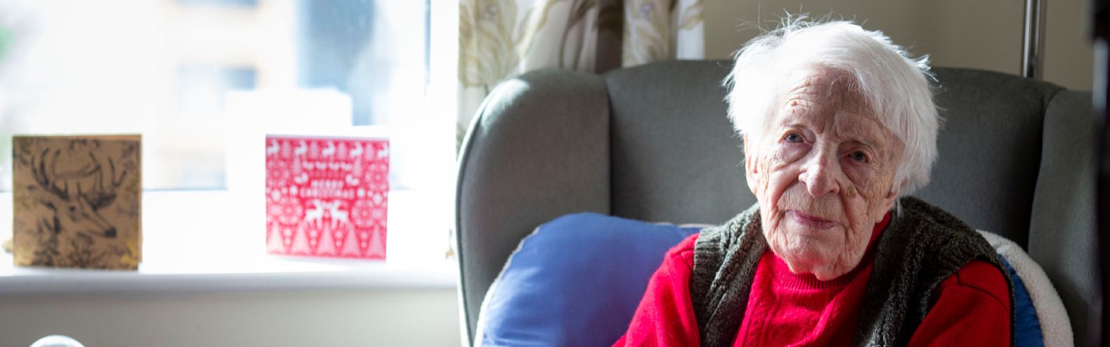 Marjorie sits alone in her living room, looking slightly sad