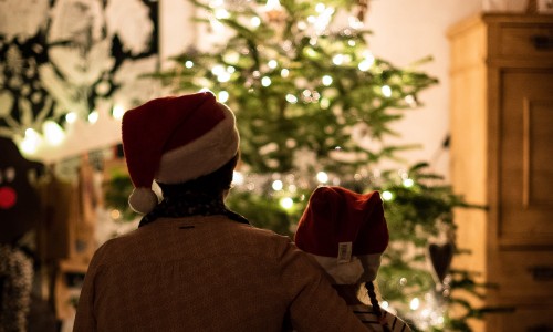 Two figures silhouetted against a Christmas tree