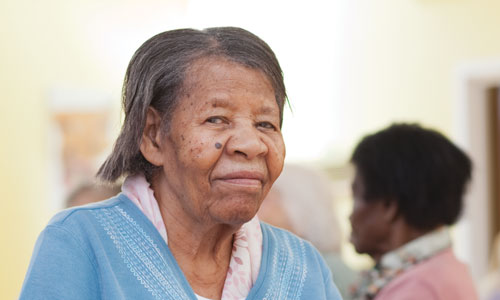 An older lady in a care home, wearing a blue cardigan
