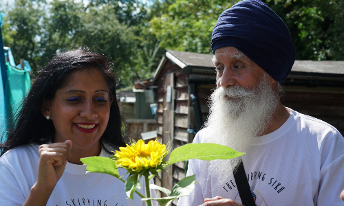 Minreet and her father Rajinder, stood in a garden, looking at a sunflower