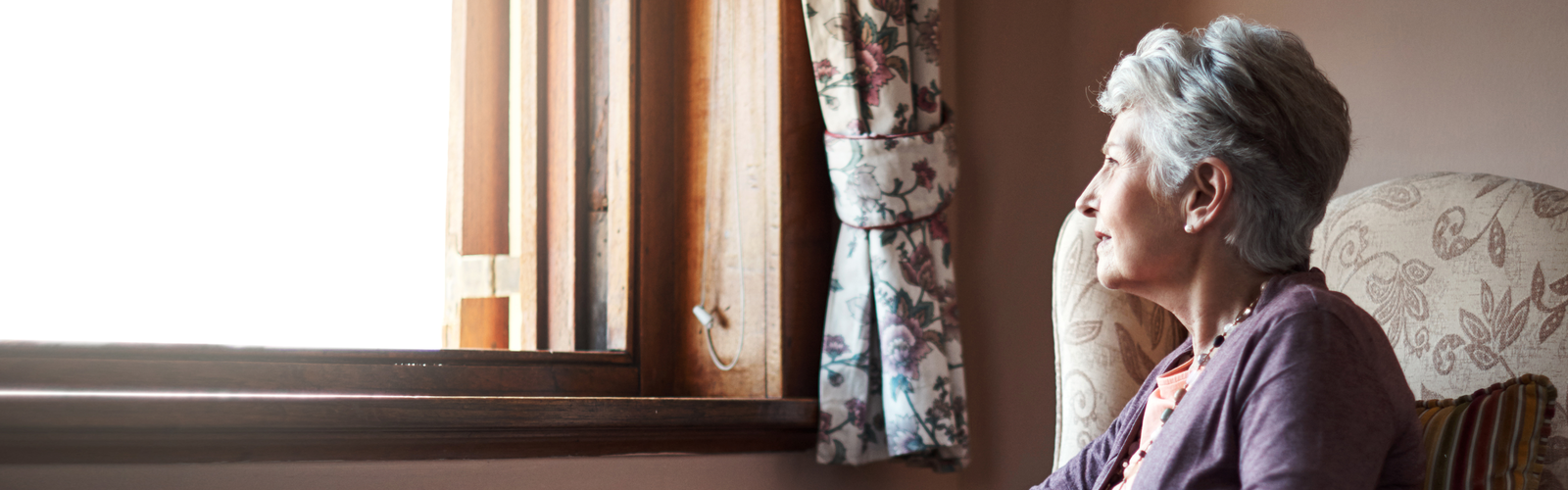 An older woman, looking out of a window