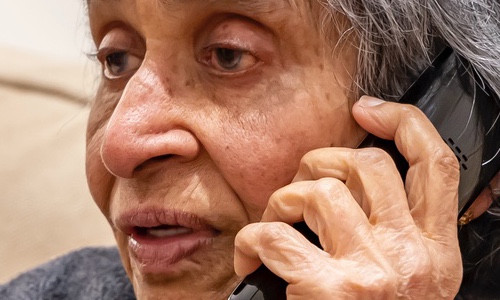 An older woman, looking anxious, speaking on the phone