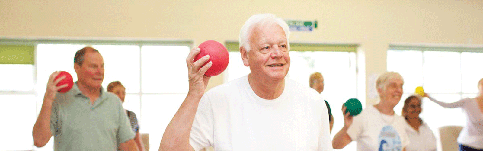 A man doing exercises with a red ball at an exercise class