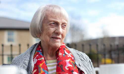 Older woman standing in front of houses