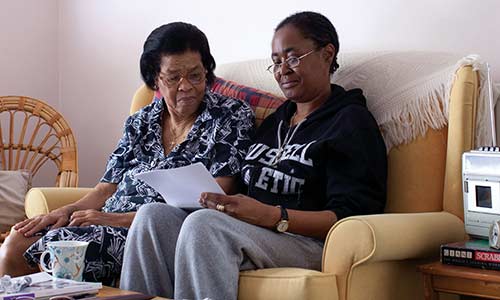 Two ladies sitting on a sofa, reading a letter