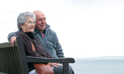 An older couple sat by the sea