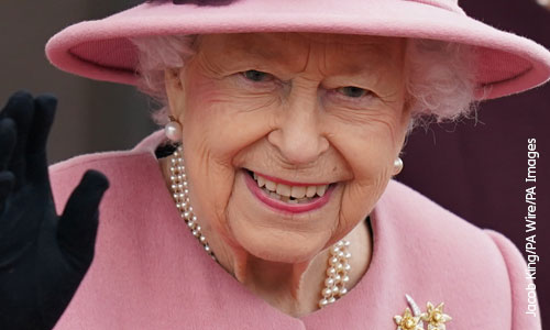 An image of Queen Elizabeth II, dressed in pink, smiling and waving at the camera