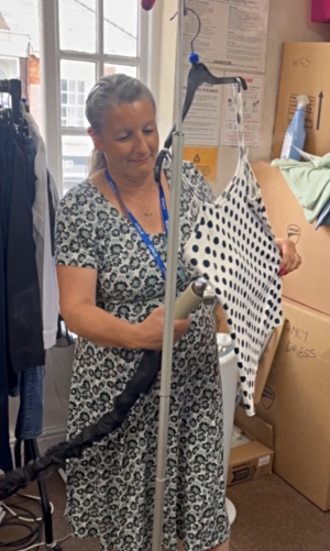 A woman steaming a top, ready for display in a charity shop