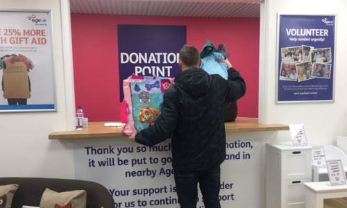 A man donates items to his Age UK shop