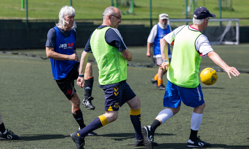 A group of four older men tackle each other during walking football