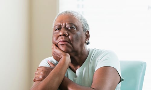 An older woman, with her chin resting on her hand, sat at a table