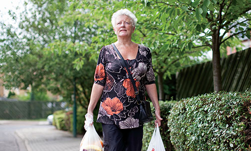 An older lady carrying shopping and walking