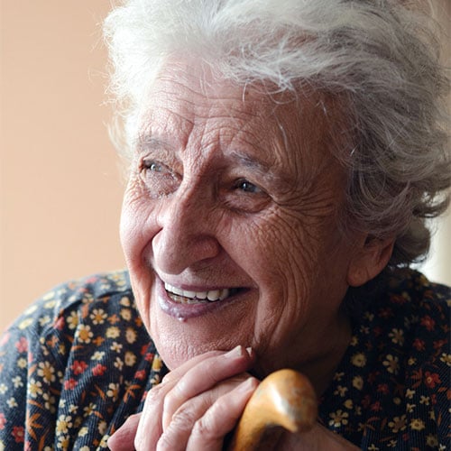 Older woman smiling and leaning on walking stick