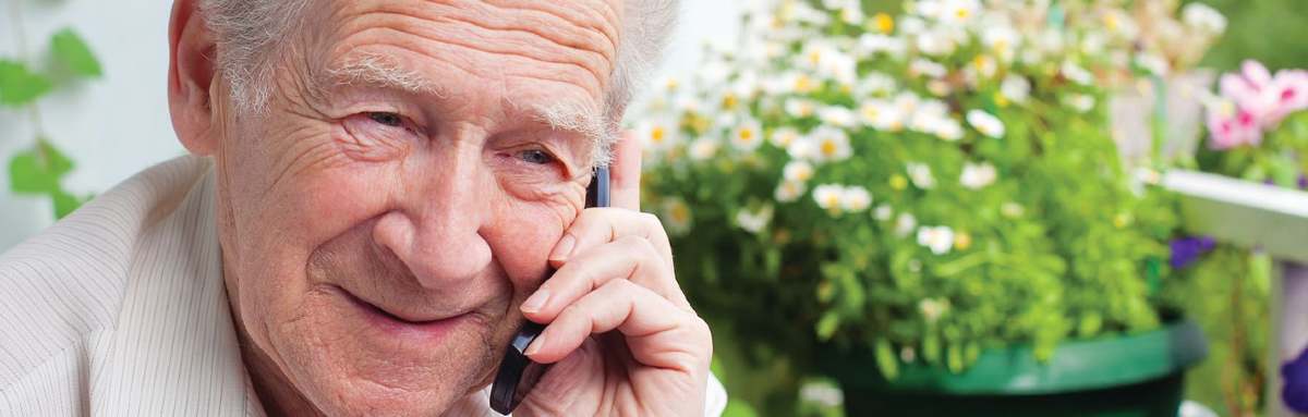 An older man takes a phone call, smiling