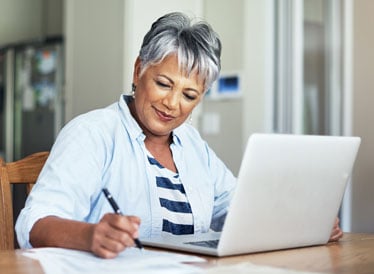 Woman on laptop making notes