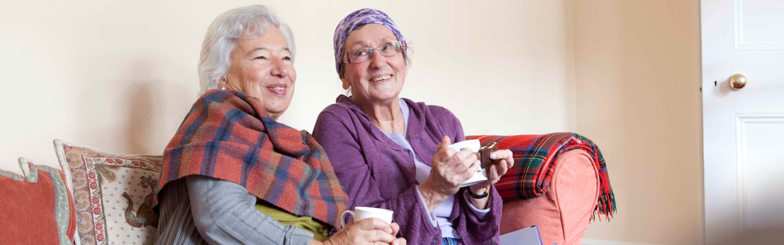Two older ladies sit together on the sofa