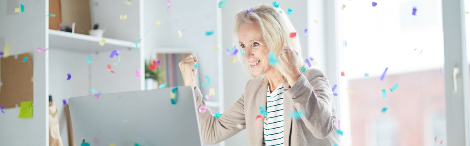 woman at her computer celebrating a lottery win with confetti
