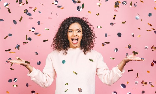 a woman celebrating her lottery win while surrounded by confetti
