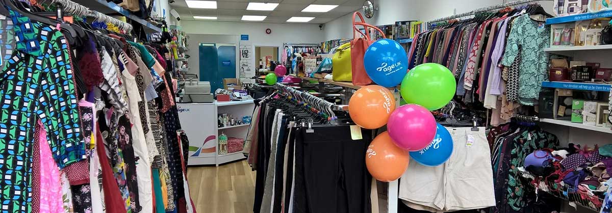 An Age UK charity shop with colourful balloons in the foreground