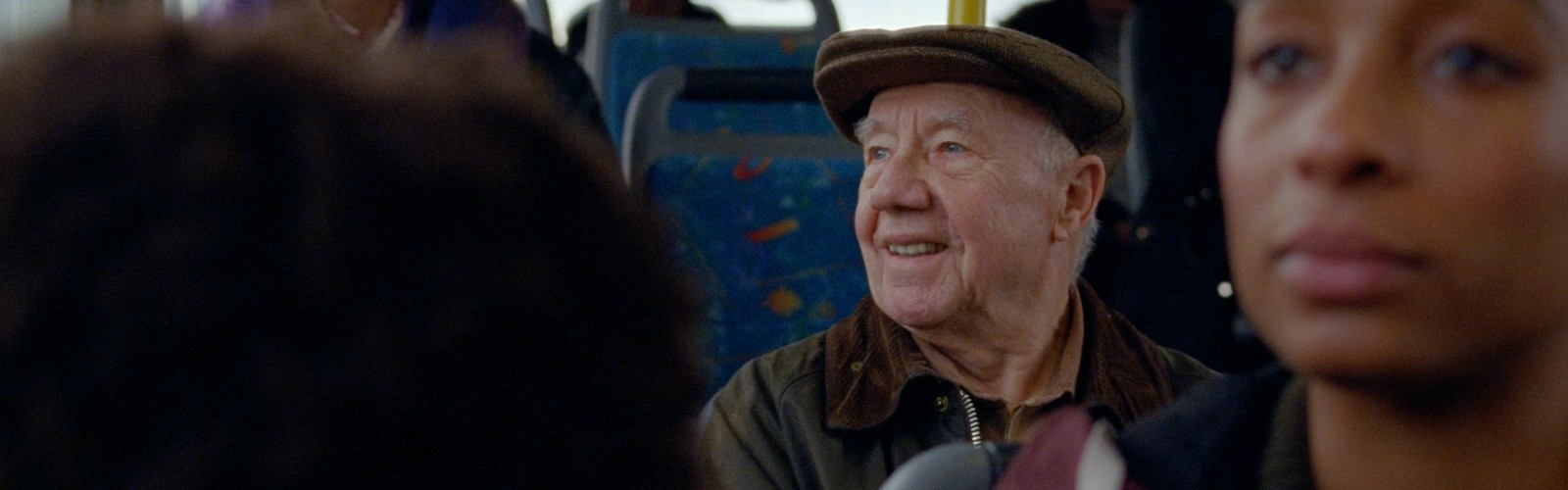 An older man riding the bus, smiling