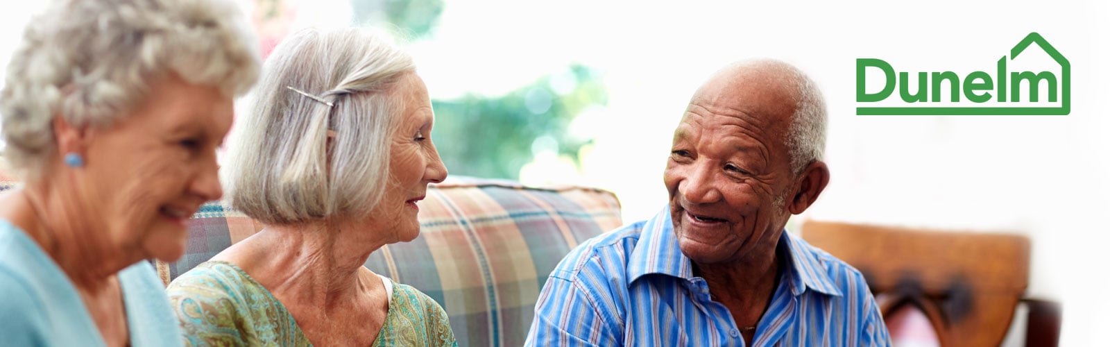 A group of older people smile and talk together