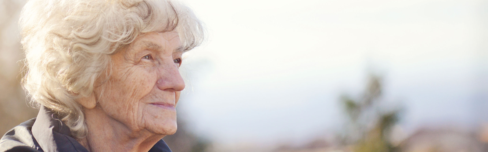 An older woman looks thoughtfully into the distance