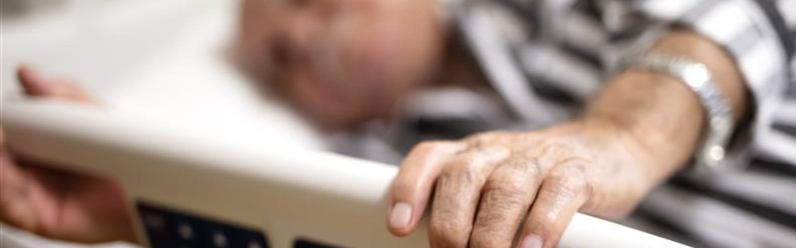 An older person lies on a trolley in A&E