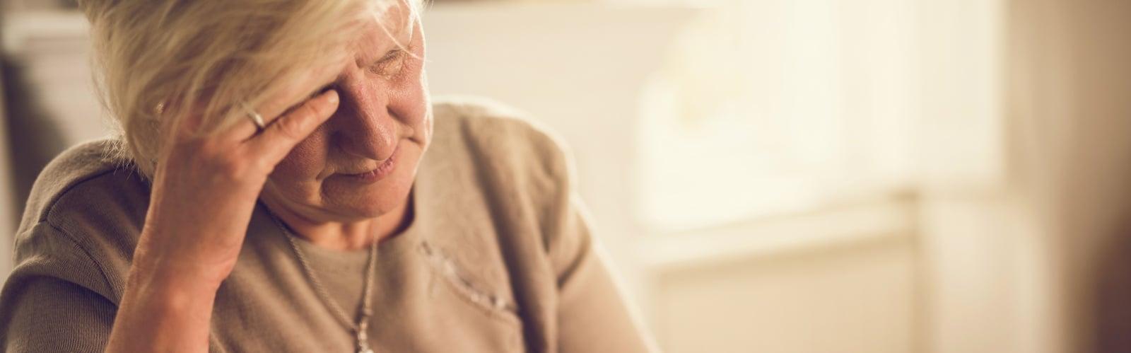 A woman in her 60s, taking medication and looking pained