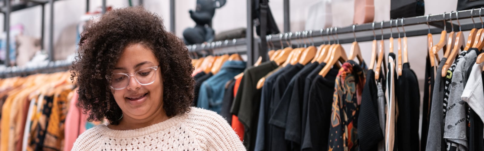 A young woman volunteering in an Age UK charity shop