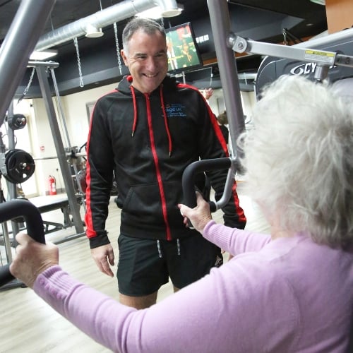 A fitness instructor talks with an older woman with grey hair