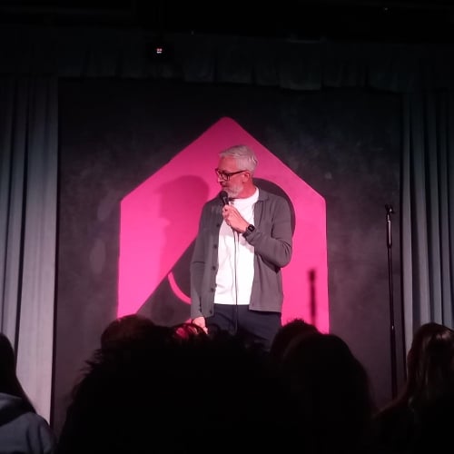 A man with grey hair doing stand-up comedy